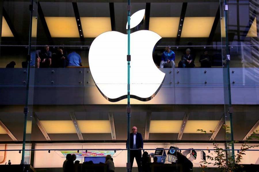 A customer stands underneath an illuminated Apple logo as he looks out the window of the Apple store located in central Sydney, Australia, May 28, 2018. Reuters/Files