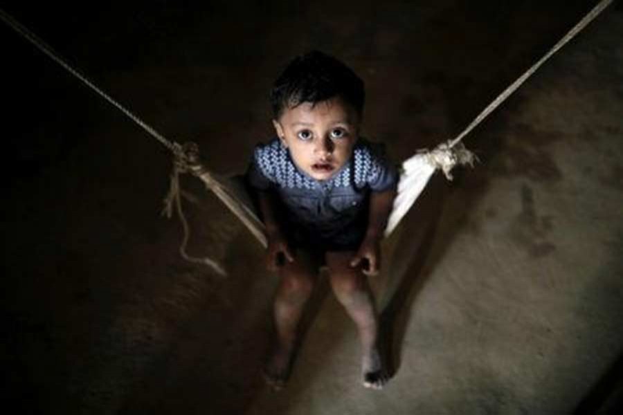 A Rohingya refugee child reacts to the camera while sitting on a cradle at the Balikhali camp in Cox's Bazar, Bangladesh, November 14, 2018. Reuters