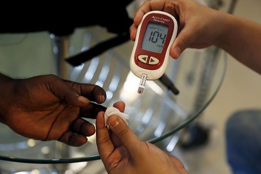 A paramedic (R) checks the blood sugar level of a diabetic patient. Reuters photo