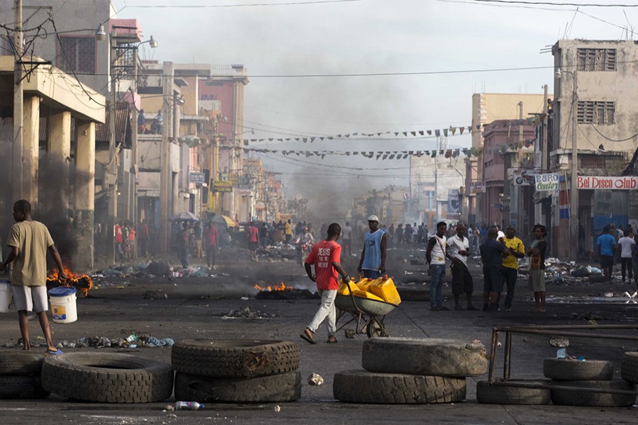 Residents walk amid road blocks placed by anti-government protesters along Boulevard Jean-Jacques Dessalines, a main commercial artery, during a strike against alleged government corruption in Port-au-Prince, Haiti on Wednesday — AP photo