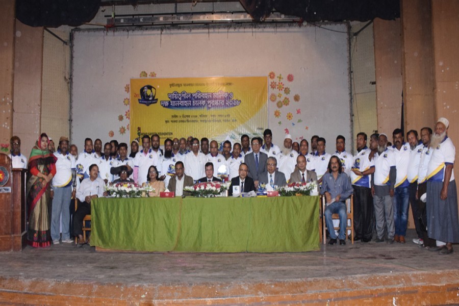 Mostafa Azad Chowdhury of Agamoni Express and Romesh Chandra Ghosh of Shyamoli Paribahan posing for photograph with 48 drivers after receiving crests and certificates in the city on Saturday — FE Photo