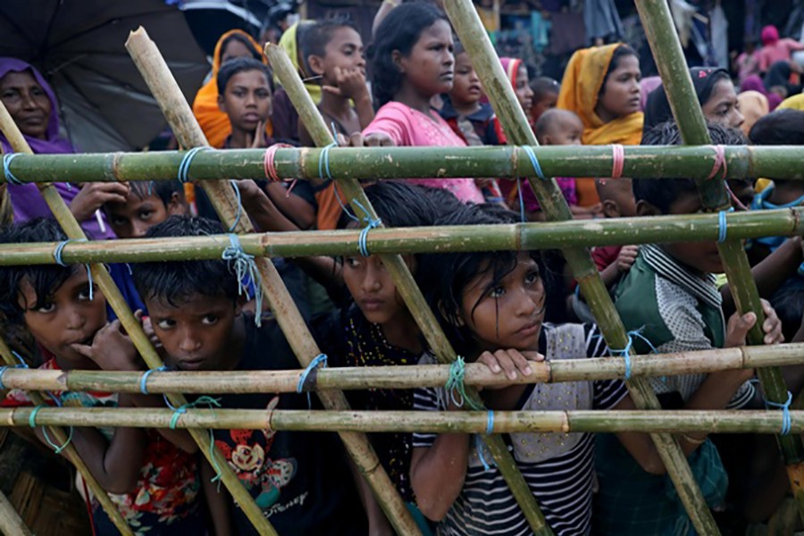 Rohingya refugees look through a fence as they wait outside of aid distribution premises at a refugee camp in Cox's Bazar, Bangladesh October 8, 2017. - Reuters