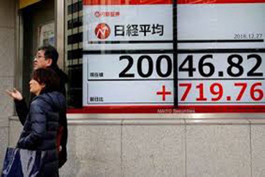 Pedestrians talk in front of an electronic board showing Nikkei share average outside a brokerage in Tokyo, Japan, December 27, 2018. Reuters