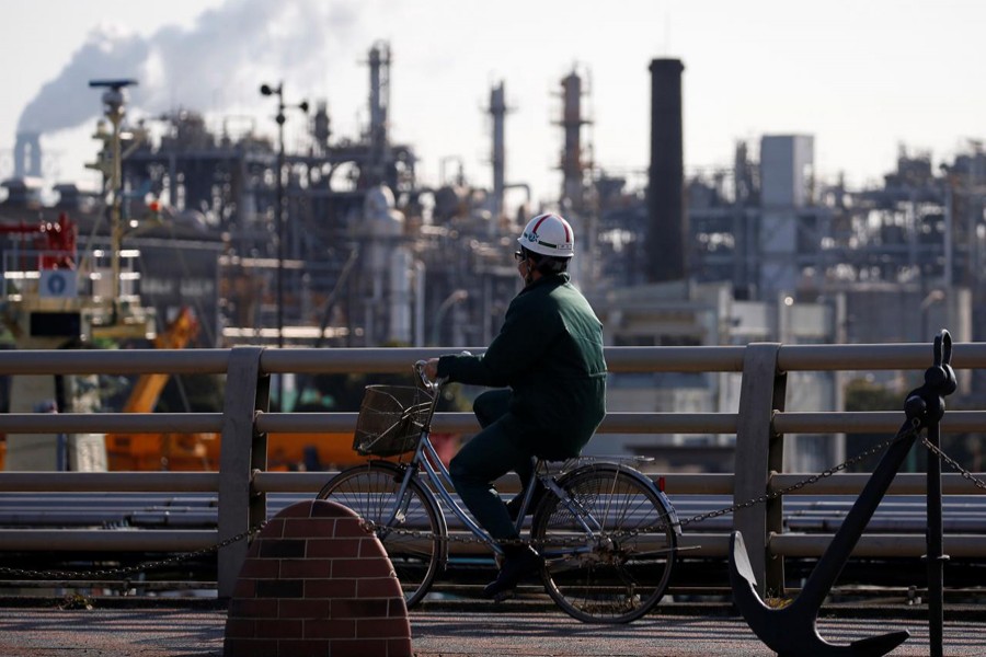 A worker cycles near a factory at the Keihin industrial zone in Kawasaki, Japan, February 28, 2017. Reuters/Files