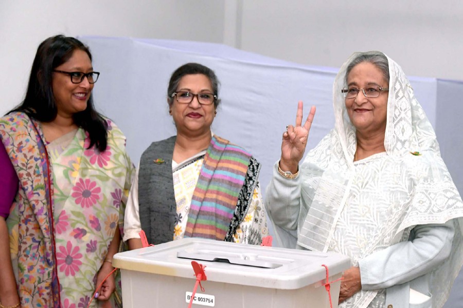 Prime Minister Sheikh Hasina flashes her V-sign after casting her vote at Dhaka City College centre on Sunday. Her sister Sheikh Rehana and daughter Saima Wazed were present. Photo: PID