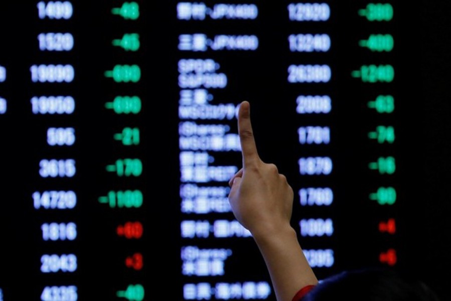 A woman points to an electronic board showing stock prices as she poses in front of the board after the New Year opening ceremony at the Tokyo Stock Exchange (TSE), held to wish for the success of Japan's stock market, in Tokyo, Japan, January 4, 2019. Reuters