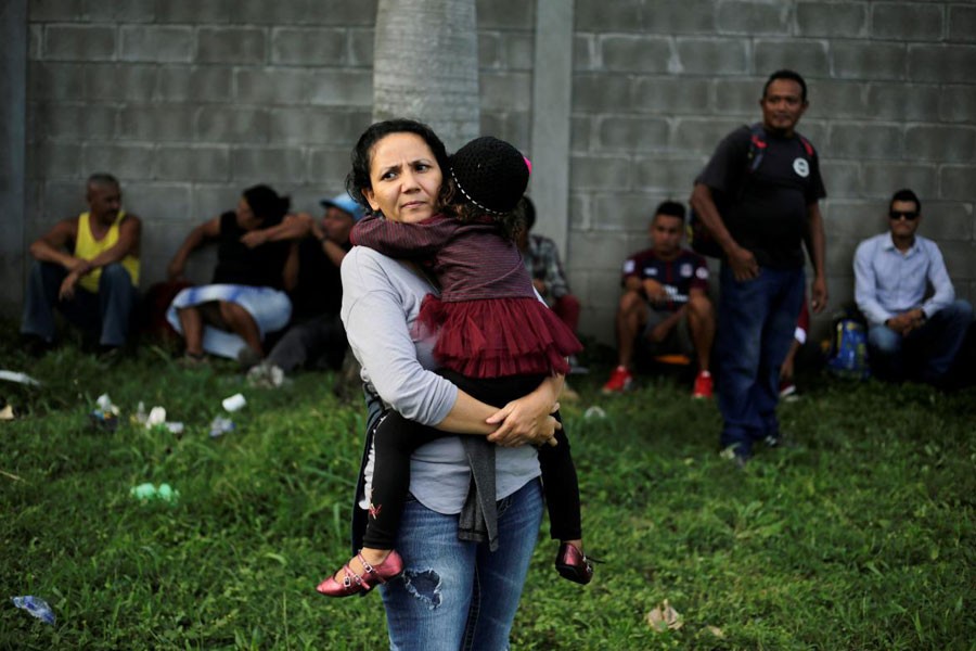 A Honduran woman carries her daughter as they wait to leave with a new caravan of migrants, set to head to the United States, at a bus station in San Pedro Sula, Honduras, January 14, 2019 - REUTERS/Jorge Cabrera