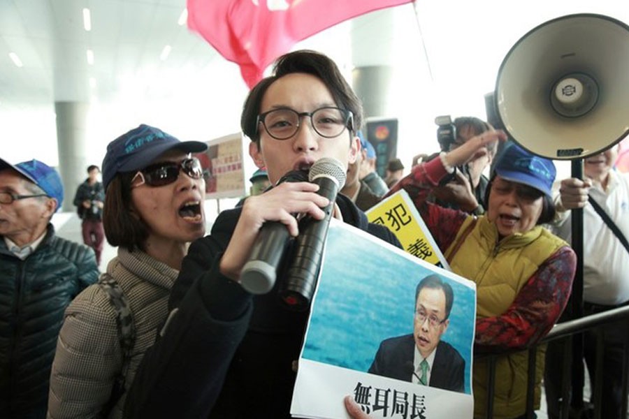 Pro-democracy activist Figo Chan, holding a sign showing Secretary for Constitutional and Mainland Affairs Patrick Nip, clashes with pro-Beijing protesters over the Chinese national anthem law controversy outside the Legislative Council Complex in Hong Kong, China, January 23, 2019 - REUTERS/Yuyang Wang