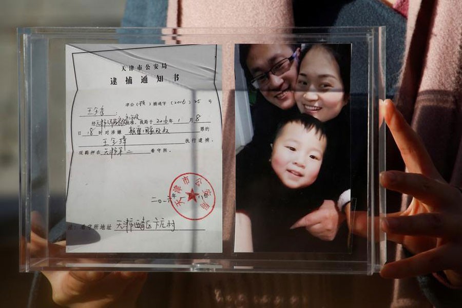 Li Wenzu, the wife of prominent Chinese rights lawyer Wang Quanzhang, holds a box with a family picture and the detention notice for her husband before shaving her head in protest in Beijing, China, December 17, 2018 - REUTERS/Thomas Peter/File Photo