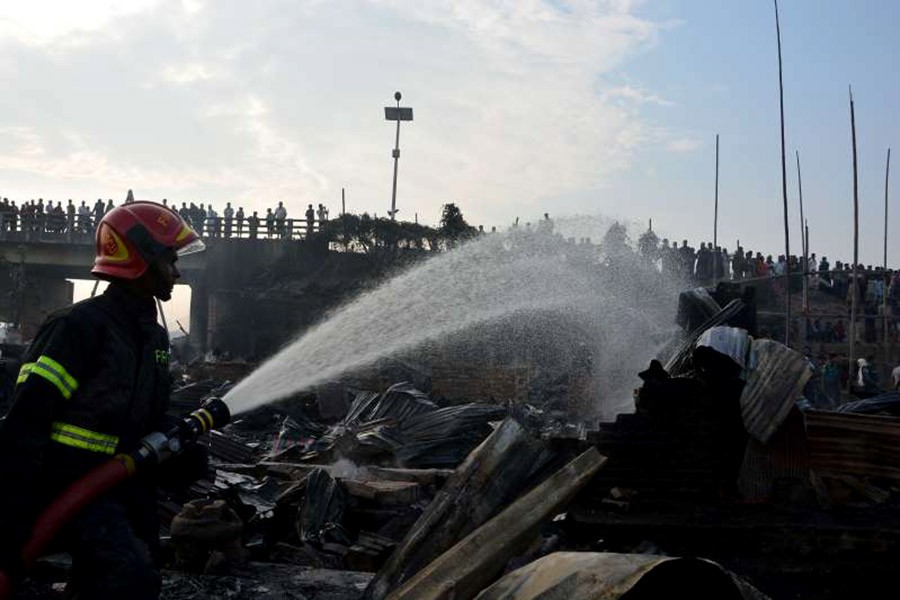 A fire fighter working to extinguish fire at a slum in Chattogram on Sunday. -Reuters Photo