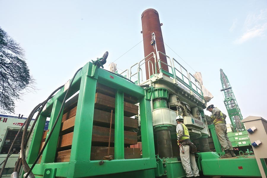 Two persons monitoring a screw-based piling system of metro rail construction project in the city on Monday — FE Photo