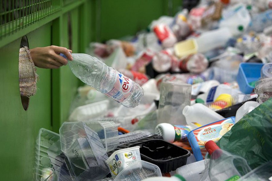 A woman depositing a plastic bottle in a recycling bin in Worcestershire, UK. Photo: Collected