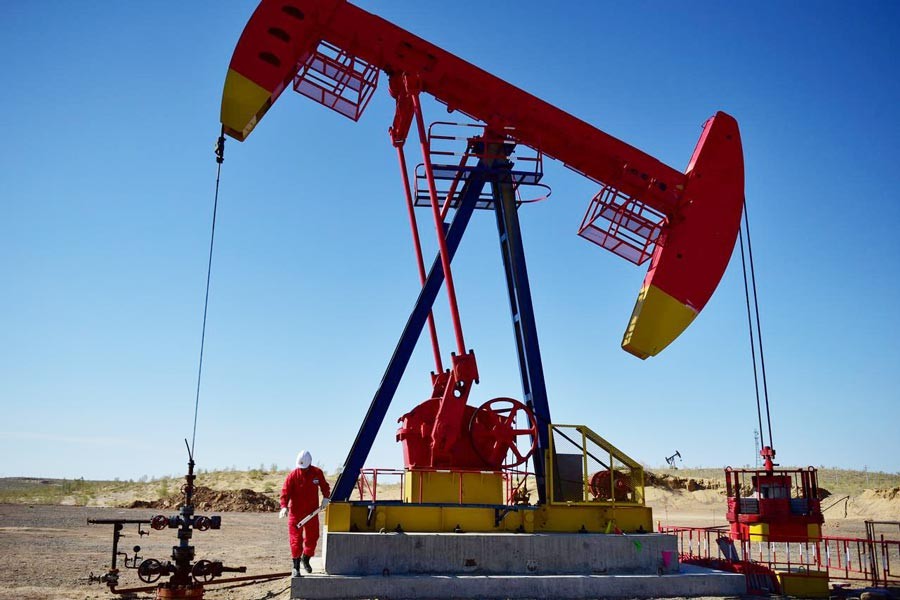 A PetroChina worker inspects a pump jack at an oil field in Tacheng, Xinjiang Uighur Autonomous Region, China 	— Reuters