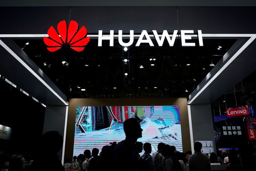 People walk past a sign board of Huawei at CES (Consumer Electronics Show) Asia 2018 in Shanghai, China June 14, 2018. Reuters