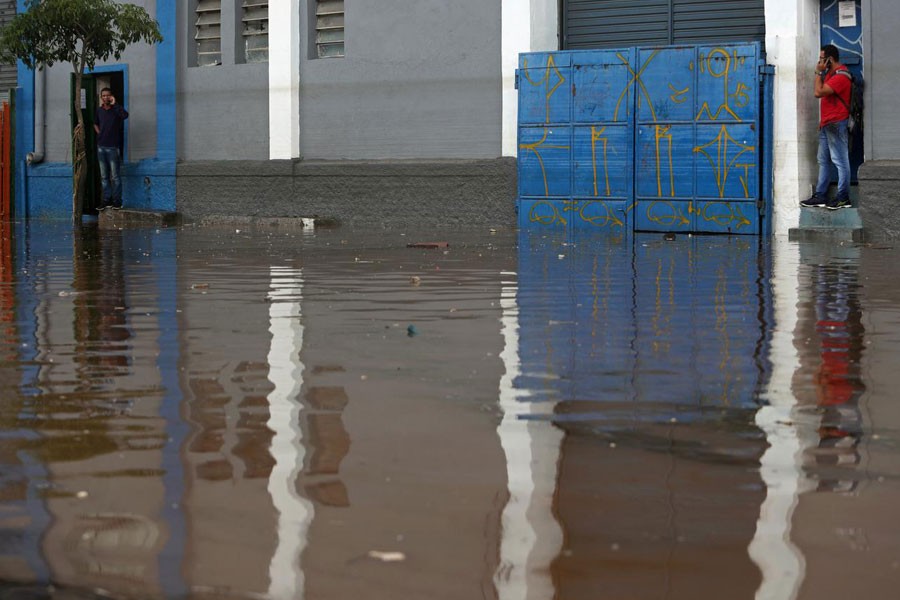 Men wait for the water level to drop in a flooded street after heavy rains in Vila Prudente neighbourhood in Sao Paulo, Brazil March 11, 2019 - REUTERS/Amanda Perobelli