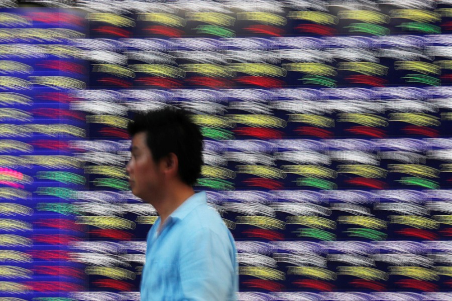 Passersby walk past in front of an electronic stock quotation board outside a brokerage in Tokyo, Japan, September 28, 2018. Reuters/Files