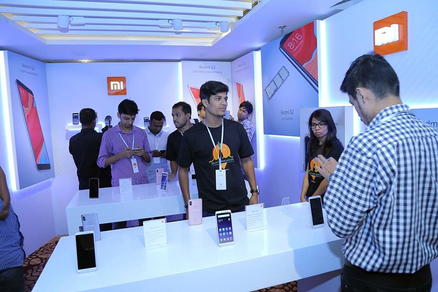 A potential customer looks at a Xiaomi handset on display at an Mi Outlet in Dhaka — Facebook photo