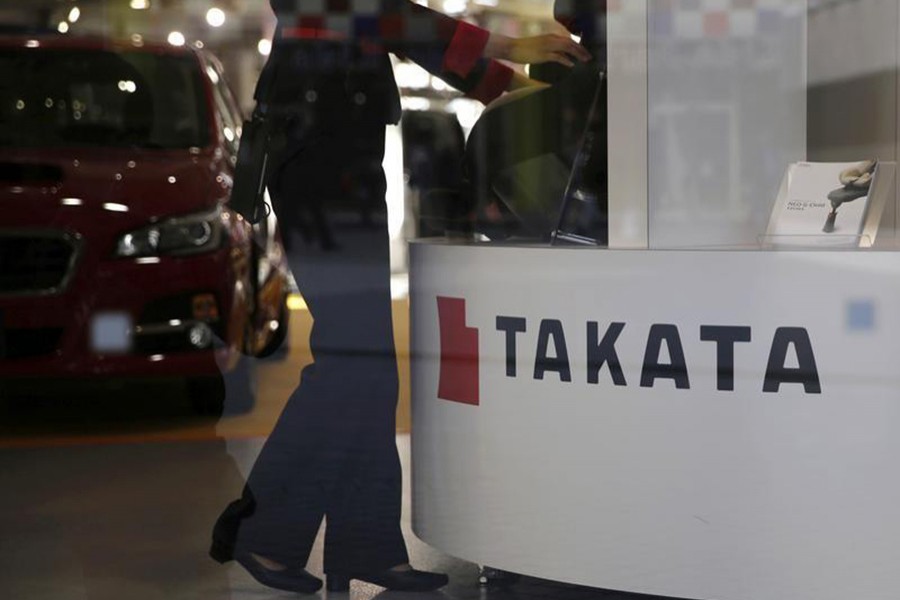 A woman stands next to a logo of Takata Corp at a showroom for vehicles in Tokyo, Japan on November 6, 2015 — Reuters/Files