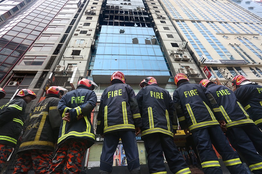 Firefighters stand outside the FR tower at Banani after putting out a deadly blaze that tore through several floors of the skyscraper, killing at least 26 people — FE photo