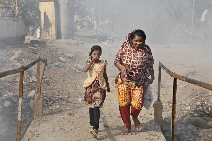 A girl trying to cover her face using her hand in an attempt to protect herself from heavily polluted air as she, along with her mother, crosses a bridge in the city's Lalbagh Beribadh area in this undated Focus Bangla photo