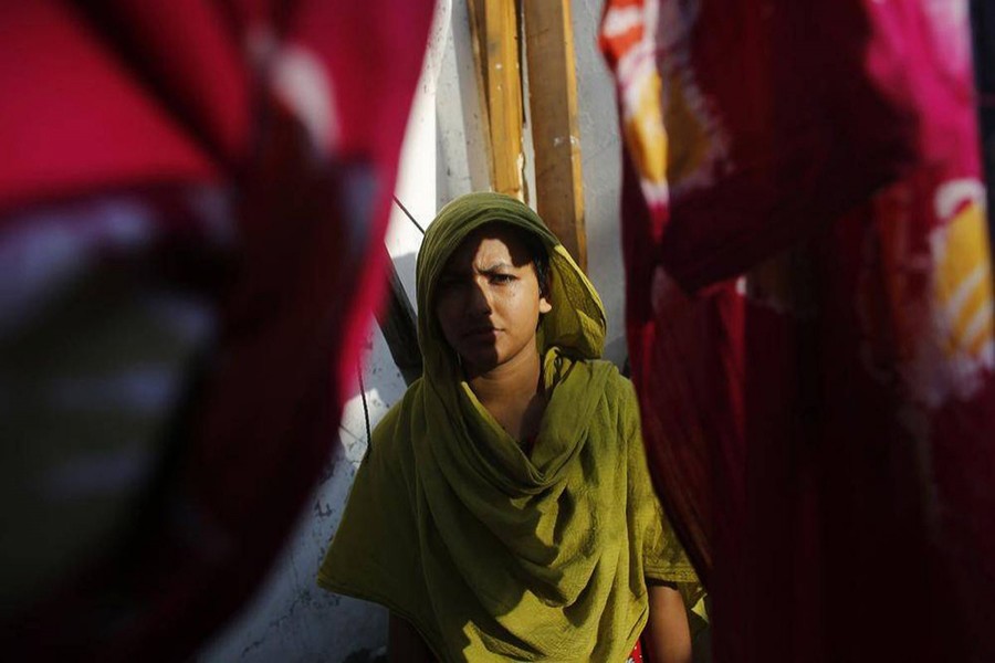 Khodeja, 25, who was rescued from the rubble of the collapsed Rana Plaza building, stands in front of her slum house in Savar.  Khodeja is unable to work due to a spinal injury caused by the accident — Reuters/Files