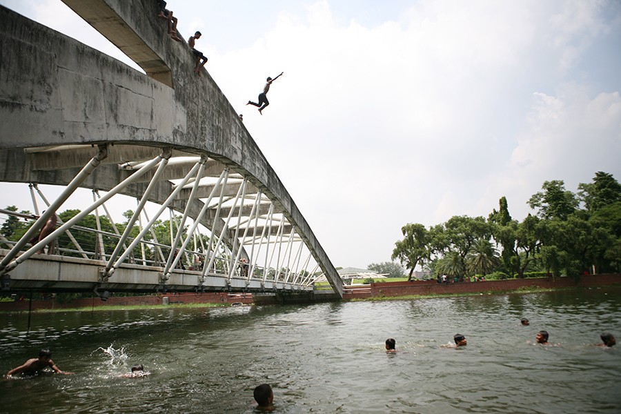 Boys jumping into the water of a lake in Dhaka city to cool themselves off during a hot summer day — FE/Files