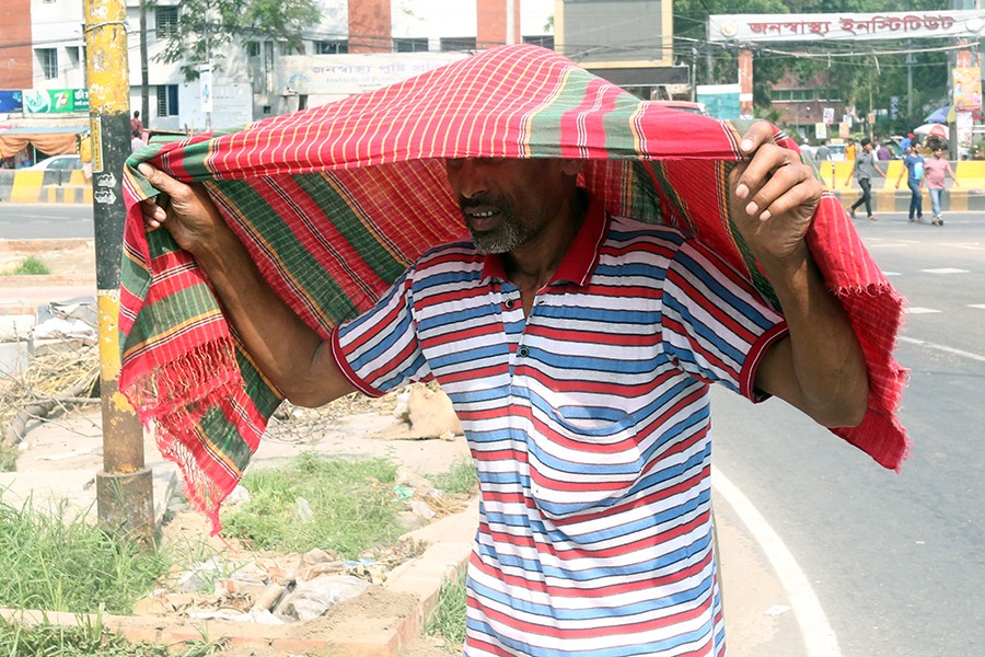 A man using his towel to protect himself from the blazing sun in Dhaka city. FE/Files