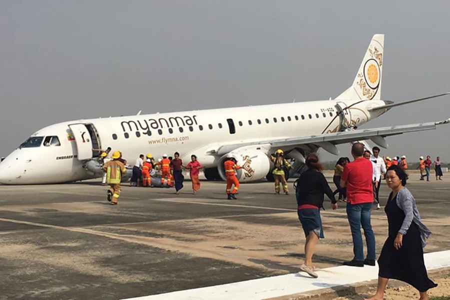 Firefighters attend to the scene after Myanmar National Airlines flight UB103 landed without a front wheel at Mandalay International Airport in Tada-U, Myanmar on May 12, 2019 in this photo collected from social media