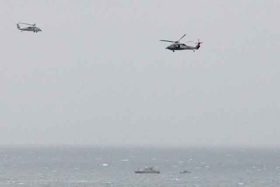 An Iranian Revolutionary Guard boat is seen near the US aircraft carrier USS George H. W. Bush in the Strait of Hormuz as US Navy helicopters hover nearby on March 21, 2017. Reuters