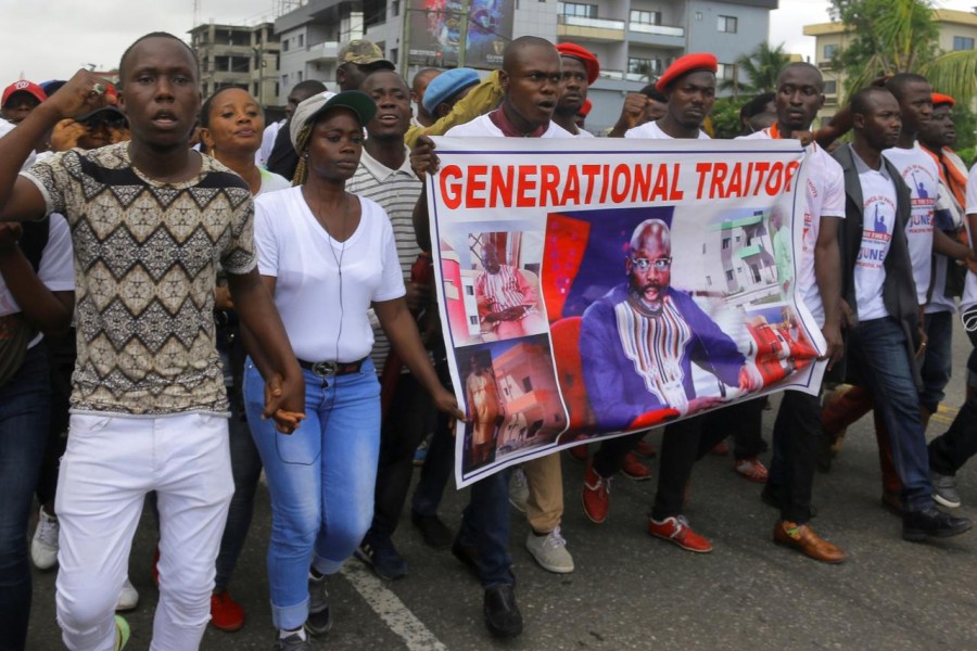 People carry a banner depicting Liberia's President George Weah as they march during a protest to voice discontent towards the presidency of Weah, whose policies they see as having failed to curb economic decline and mitigate corruption, in Monrovia, Liberia June 7, 2019 - REUTERS/James Giahyue