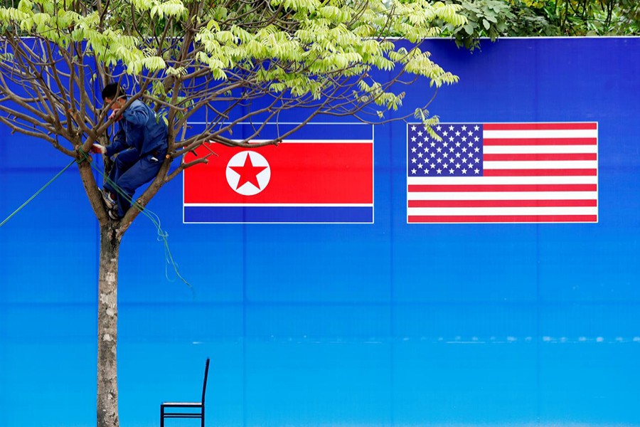 A worker is seen on a tree next to a banner showing North Korean and US flags ahead of the North Korea-US summit in Hanoi, Vietnam on February 25, 2019 — Reuters photo