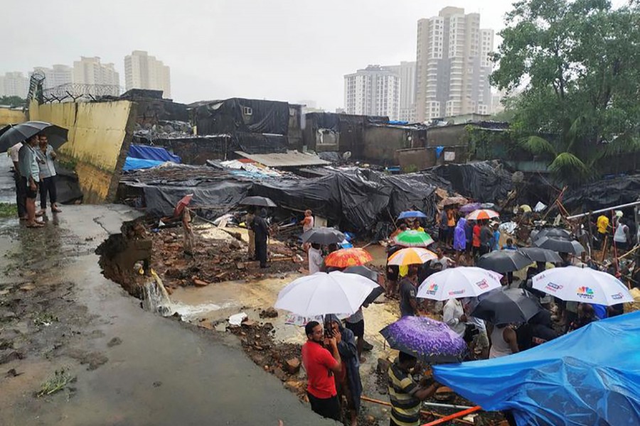 People stand among the debris after a wall collpased on hutments due to heavy rains in Mumbai, India on Tuesday — Reuters photo