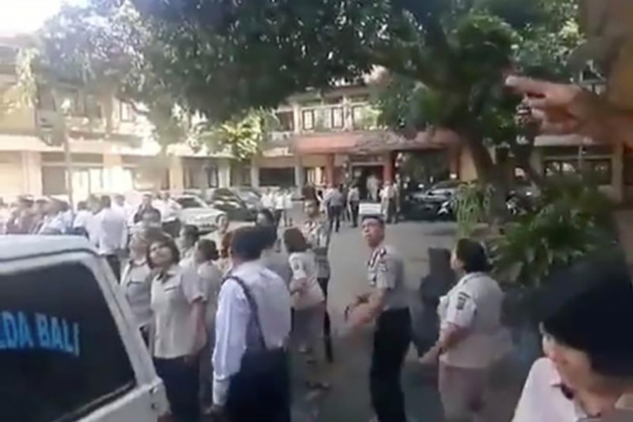 People gathered outside look toward a building, as an undersea quake struck south of Bali, at Barat Daya in Nusa Dua, Bali, Indonesia on Tuesday, in this picture obtained from social media. Mandatory credit: Thoriq Rizky via Reuters