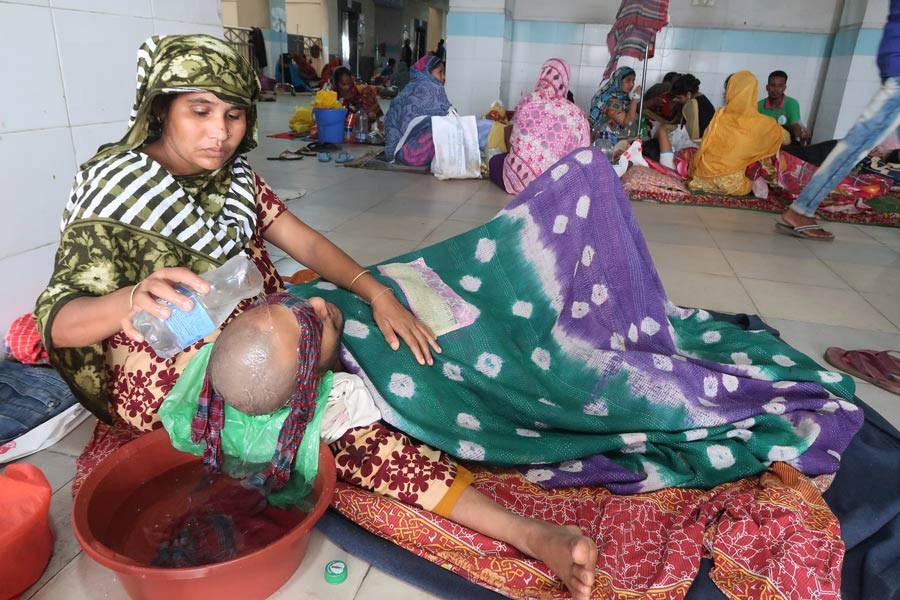 A mother nursing her son on the hospital floor after the second-year honours student got admitted to Mugda Medical College and Hospital in the capital with dengue fever on Sunday               — FE Photo by Shafiqul Alam