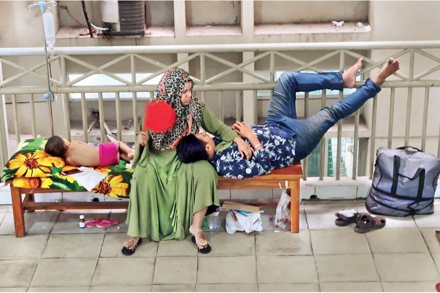 Finding no space inside hospital rooms, a couple from Tangail turned this bench into a bed for their three-year-old daughter suffering from dengue fever on a corridor of Mugda Medical College Hospital in Dhaka. The photo was taken on Tuesday — FE Photo by Shafiqul Alam