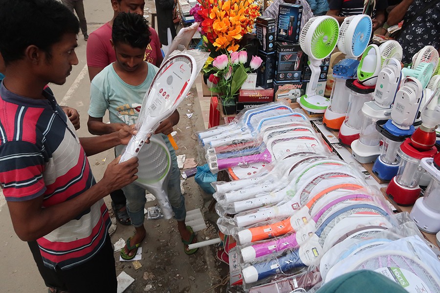 A man examining a mosquito killing bat before buying it at a makeshift shop on the Baitul Mukarram Market premises on Sunday. The demand for such tools and mosquito repellants has peaked in the wake of dengue outbreak — FE photo