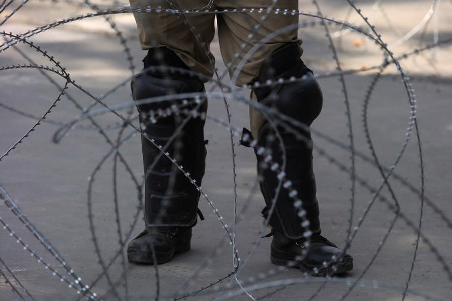 An Indian police officer stands behind the concertina wire in Srinagar, August 12, 2019 (Reuters