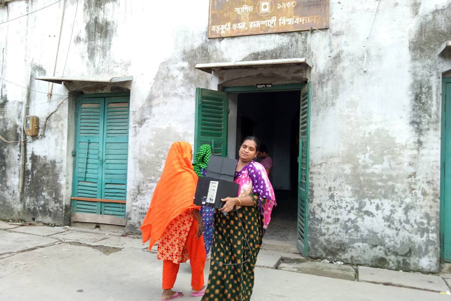 A family member of a RU employee who used to live in two rooms of the historical archaeological site of 'Boro Kuthi' is seen leaving the site with her belongings on Sunday	— FE Photo