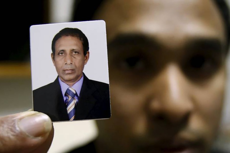 Niculas Fernando's son, George, holds up a picture of his father after an interview at his apartment in Ichikawa, Chiba Prefecture, last November. -Reuters Photo