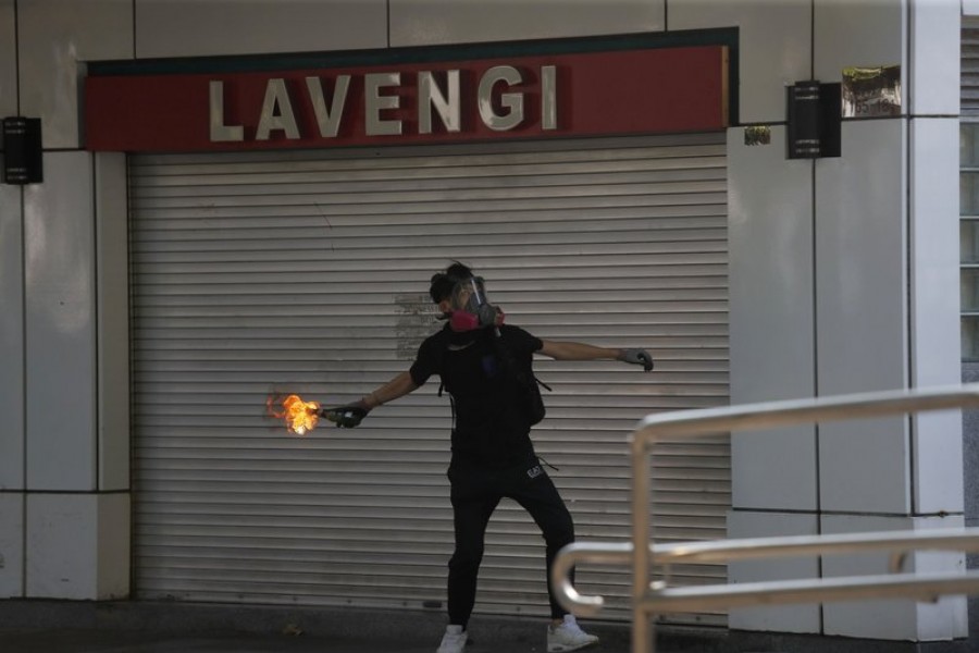 A protester throws a Molotov cocktail at a police station in Hong Kong, Sunday, Oct. 20, 2019. Hong Kong protesters again flooded streets on Sunday, ignoring a police ban on the rally and demanding the government meet their demands for accountability and political rights. (AP Photo/Kin Cheung)