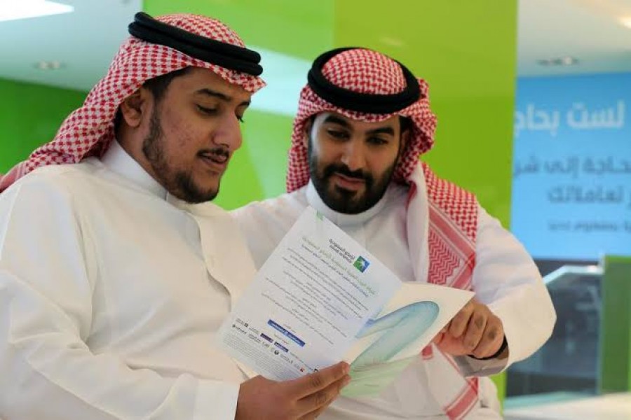 Saudi men check the prospectus of Aramco IPO, in Riyadh, Saudi Arabia, November 17, 2019. Reuters