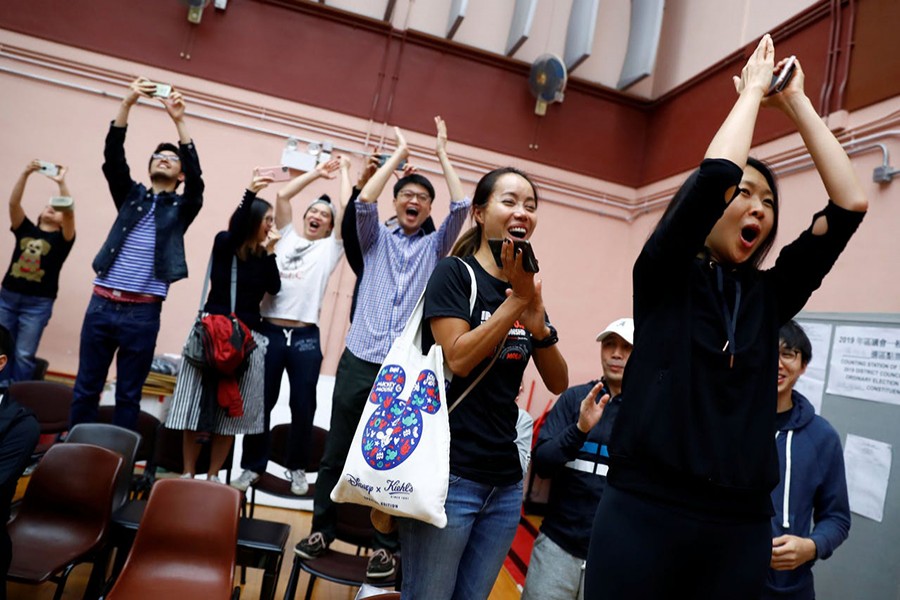 Supporters of local candidate Kelvin Lam celebrate, after it was announced he won the local council elections in his district, at a polling station in the South Horizons West district in Hong Kong, China on Monday — Reuters photo