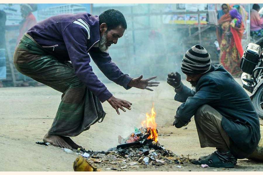 Two elderly people trying to keep themselves warm on Thursday morning by burning garbage on a road in Khulna city as a cold wave sweeps across the country      	— FE Photo