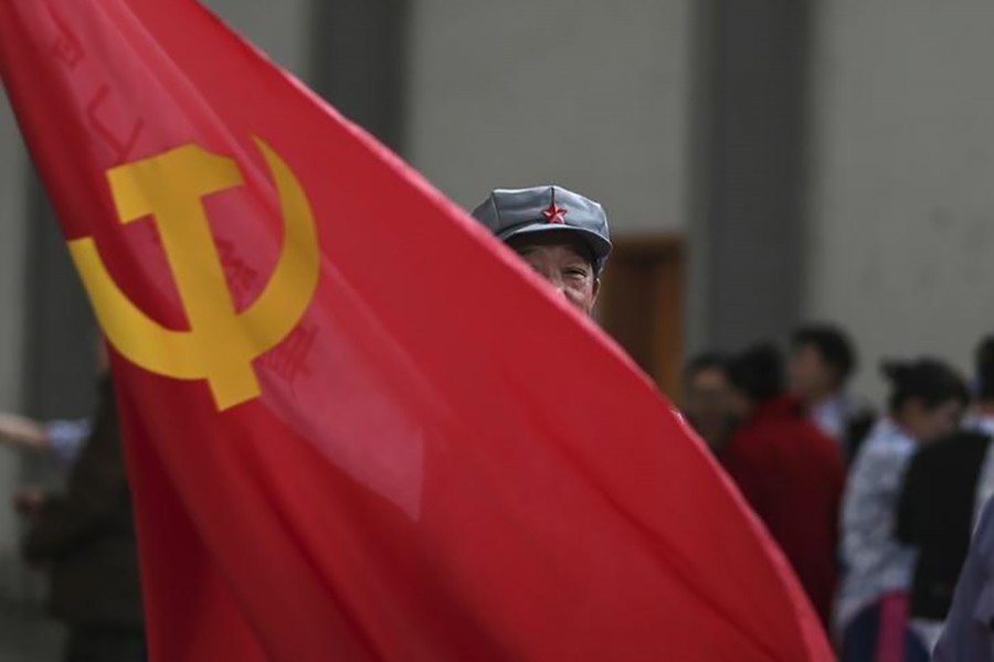 A participant waves a Chinese Communist Party flag as he waits backstage before his performance at a line dancing competition in Kunming, Yunnan province on January 31, 2015 — Reuters/Files