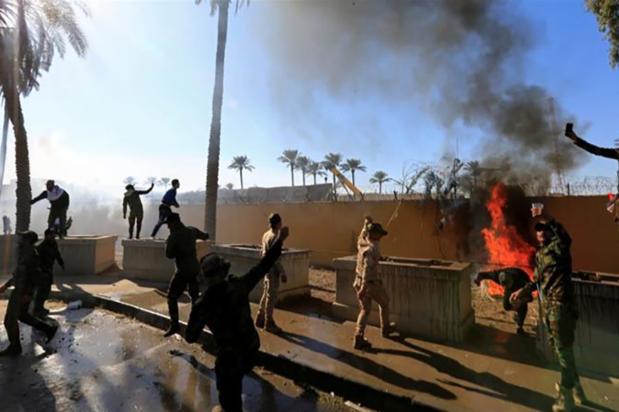 Supporters of Hashd al-Shaabi paramilitary forces (PMF) setting fire to the US embassy wall in Baghdad to condemn air attacks on their bases. -Reuters Photo