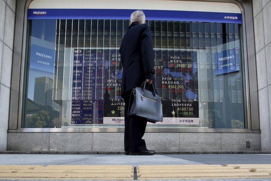 A pedestrian stands to look at an electronic board showing the stock market indices of various countries outside a brokerage in Tokyo, Japan, February 26, 2016. Reuters/Files