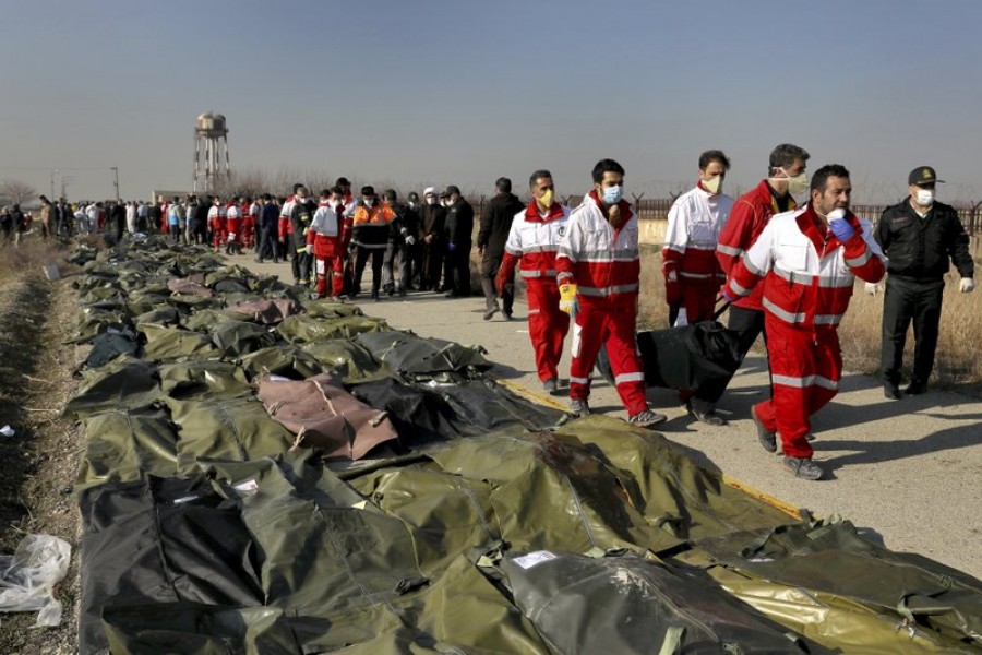 Rescue workers carry the body of a victim of a Ukrainian plane crash in Shahedshahr, southwest of the capital Tehran, Iran, Wednesday, January 8, 2020 -- AP Photo