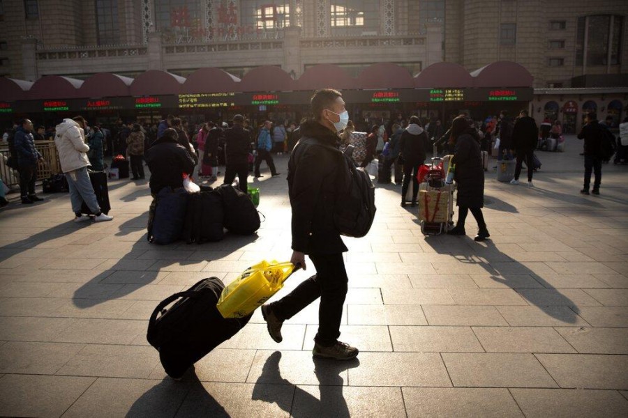 A traveler wears a facemask as he walks in front of the Beijing Railway Station in Beijing, Jan. 17, 2020. (AP Photo)