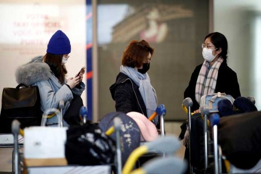 Tourists from an Air China flight from Beijing wear protective masks as they arrive at Charles de Gaulle airport in Paris, France, Jan 26, 2020. REUTERS