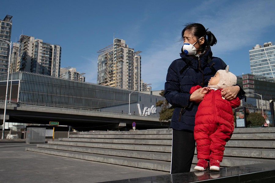 A woman wearing a face mask holds a child near a shopping mall in Beijing, China, as the country is hit by an outbreak of the new coronavirus on February 1, 2020 — Reuters photo